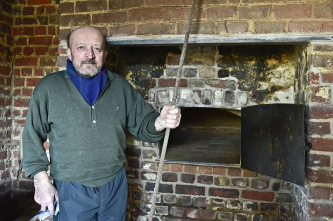 Jos Vandermersch staande bij de ovenmond met de 'broodschieter' in de hand