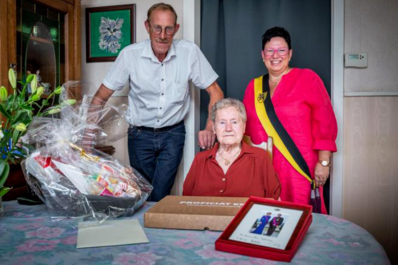 De eeuwelinge Anna Grymonprez neemt gelukwensen en geschenken in ontvangst van de Moorsleedse schepenen S. Beernaert (STER) en Geert Vanthuyne (VISIE). (Foto: HLN - Maxime Petit)